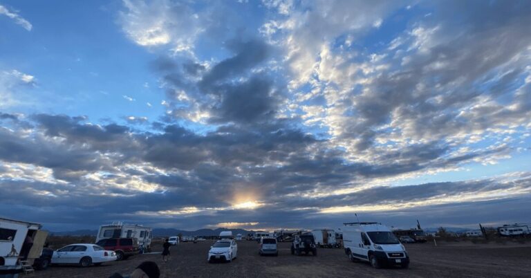 A panoramic view of Quartzsite desert with RVs spaced across the sandy landscape for boondocking.