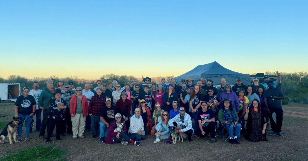 A group of RVers socializing around a campfire under the desert sky near Quartzsite. Group Photo at the 2024 Ironwood Arizona Nomadic YouTube Meetup