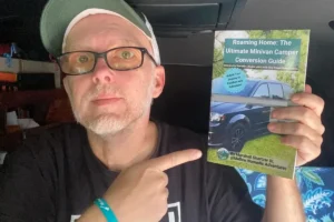 Marshall Shartzer III holding the Roaming Home minivan camper conversion guide inside Voyager